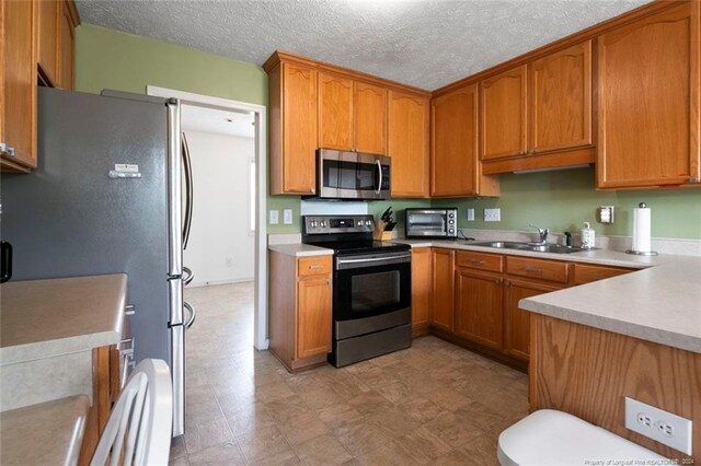 kitchen featuring a textured ceiling, sink, and stainless steel appliances