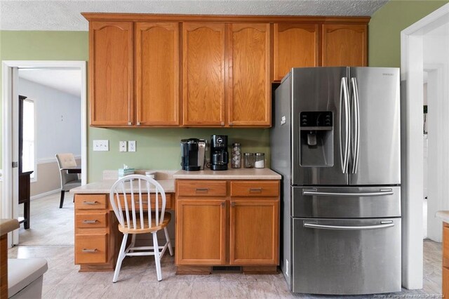 kitchen with a textured ceiling and stainless steel fridge with ice dispenser