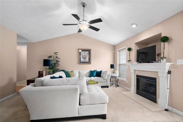 carpeted living room with a high end fireplace, ceiling fan, and vaulted ceiling