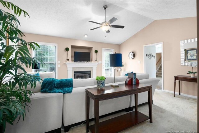 carpeted living room with ceiling fan, a textured ceiling, lofted ceiling, and a wealth of natural light