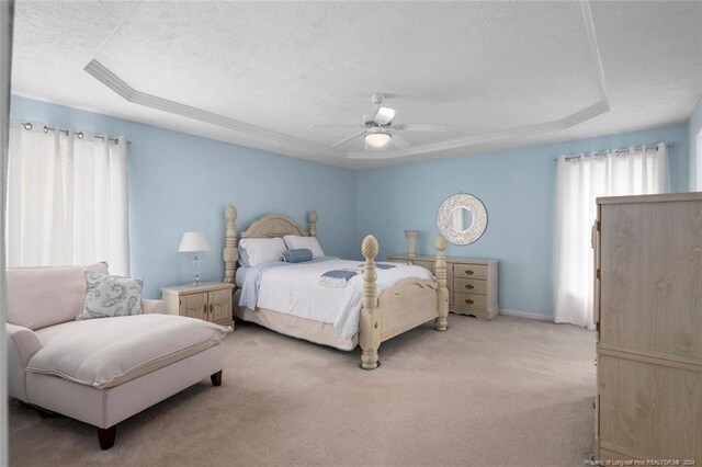 carpeted bedroom with a textured ceiling, a tray ceiling, and ceiling fan