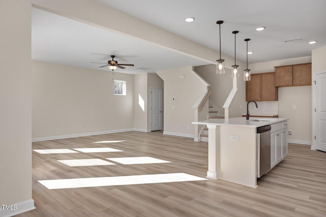 kitchen featuring decorative light fixtures, a center island with sink, stainless steel dishwasher, and light wood-type flooring