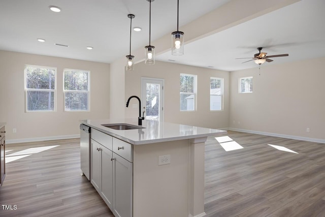 kitchen with light hardwood / wood-style floors, hanging light fixtures, sink, a center island with sink, and plenty of natural light