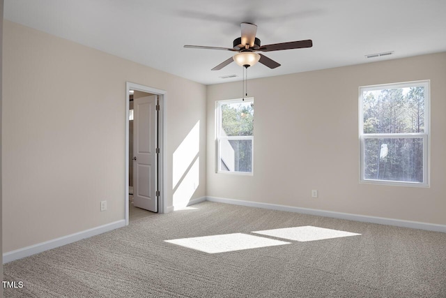 carpeted empty room featuring ceiling fan and a wealth of natural light