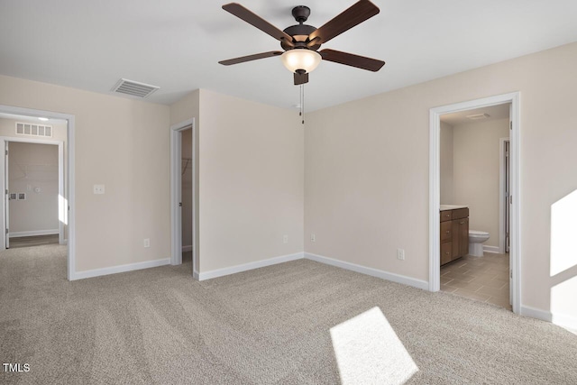 unfurnished bedroom with light colored carpet, connected bathroom, and ceiling fan