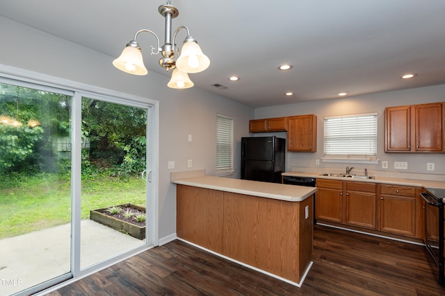 kitchen with dark wood-type flooring, kitchen peninsula, black appliances, an inviting chandelier, and plenty of natural light