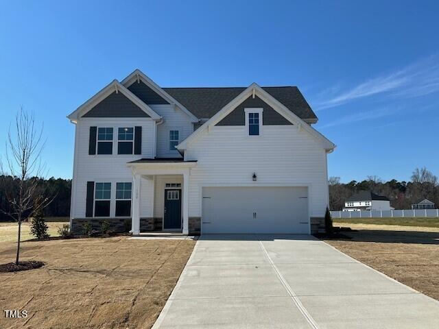 craftsman-style home with an attached garage, stone siding, and concrete driveway