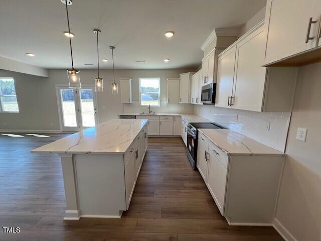 kitchen featuring a center island, electric stove, stainless steel microwave, white cabinetry, and a sink