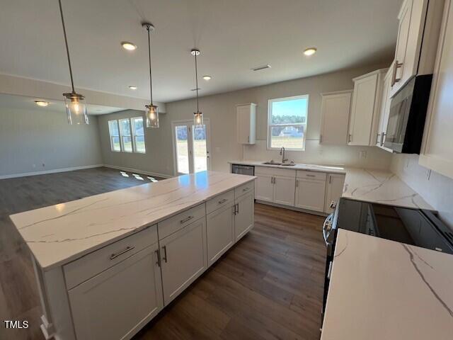 kitchen featuring a center island, a healthy amount of sunlight, white cabinets, and a sink