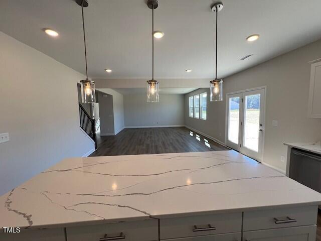 kitchen featuring a kitchen island, light stone counters, open floor plan, and dark wood-style flooring