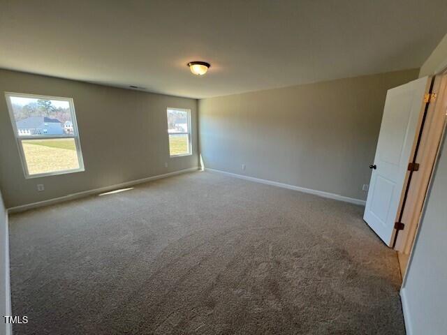 carpeted empty room featuring baseboards