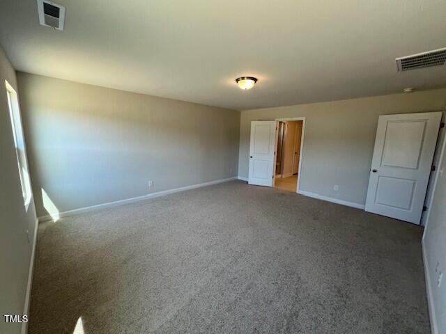 unfurnished bedroom with carpet, visible vents, and baseboards