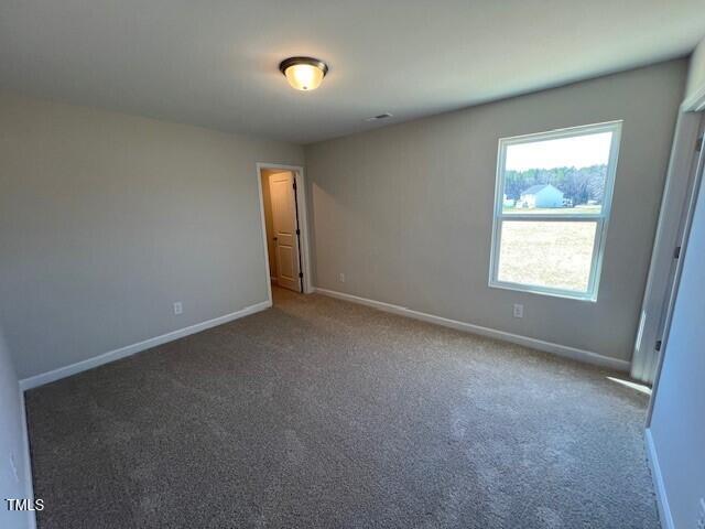 carpeted empty room featuring baseboards