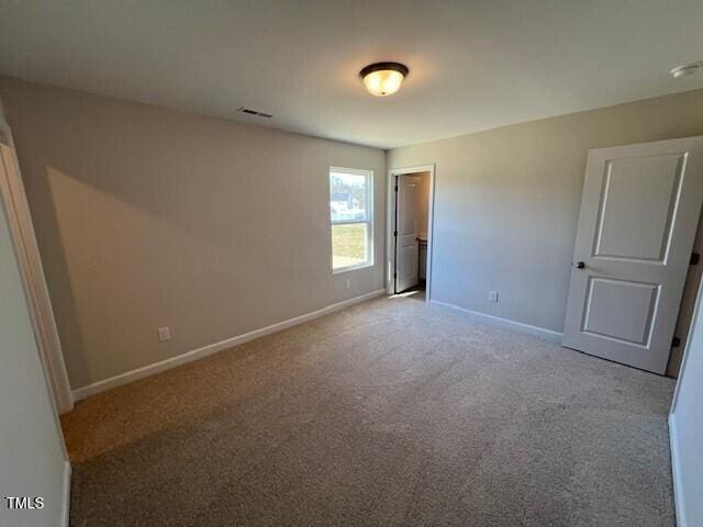 spare room with carpet, visible vents, and baseboards