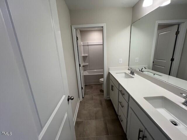 bathroom featuring double vanity, toilet, and a sink