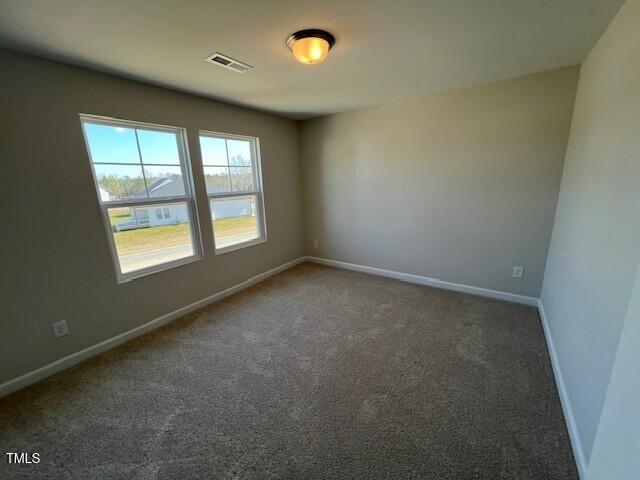 carpeted empty room featuring visible vents and baseboards