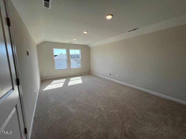 spare room with lofted ceiling, baseboards, visible vents, and carpet