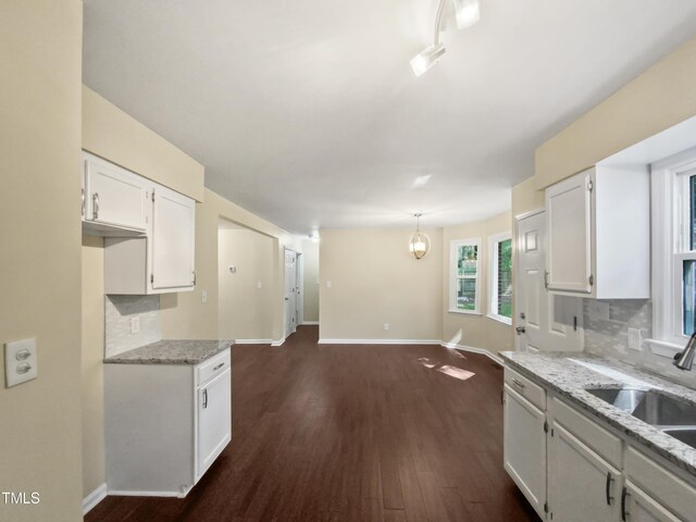 kitchen featuring light stone countertops, dark hardwood / wood-style flooring, pendant lighting, and white cabinets