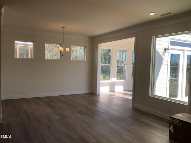 empty room featuring dark wood-type flooring, ornamental molding, and a healthy amount of sunlight