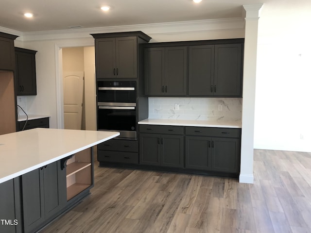 kitchen featuring wood-type flooring, double oven, decorative backsplash, and ornamental molding