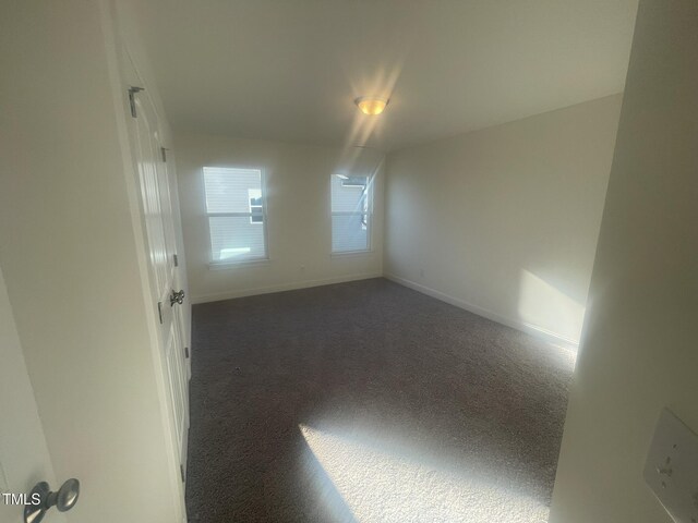 unfurnished room with dark colored carpet