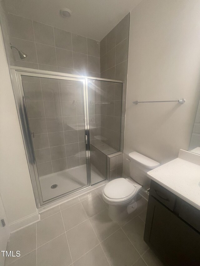 bathroom featuring toilet, an enclosed shower, tile patterned flooring, and vanity