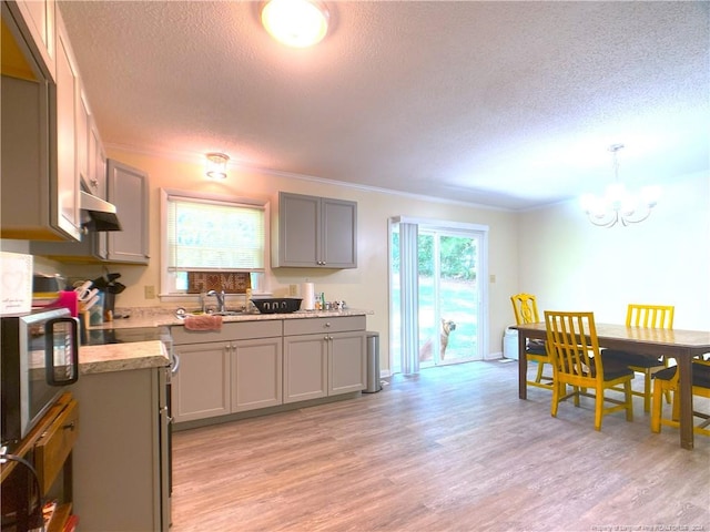 kitchen featuring pendant lighting, ornamental molding, a textured ceiling, gray cabinets, and light hardwood / wood-style floors