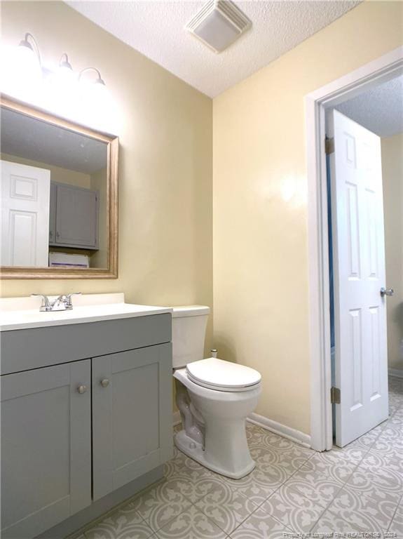 bathroom featuring a textured ceiling, vanity, and toilet