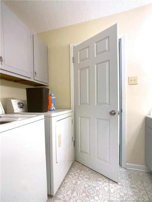 washroom with a textured ceiling, independent washer and dryer, and cabinets