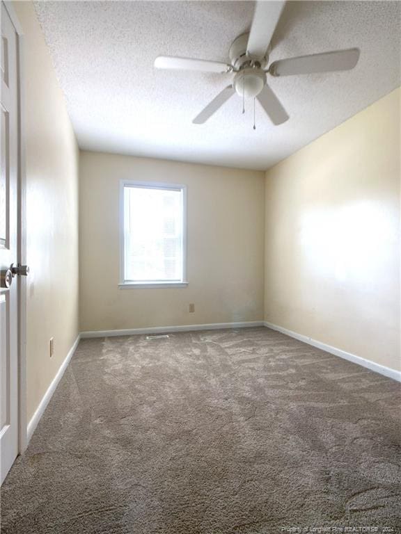 empty room featuring ceiling fan, a textured ceiling, and carpet flooring