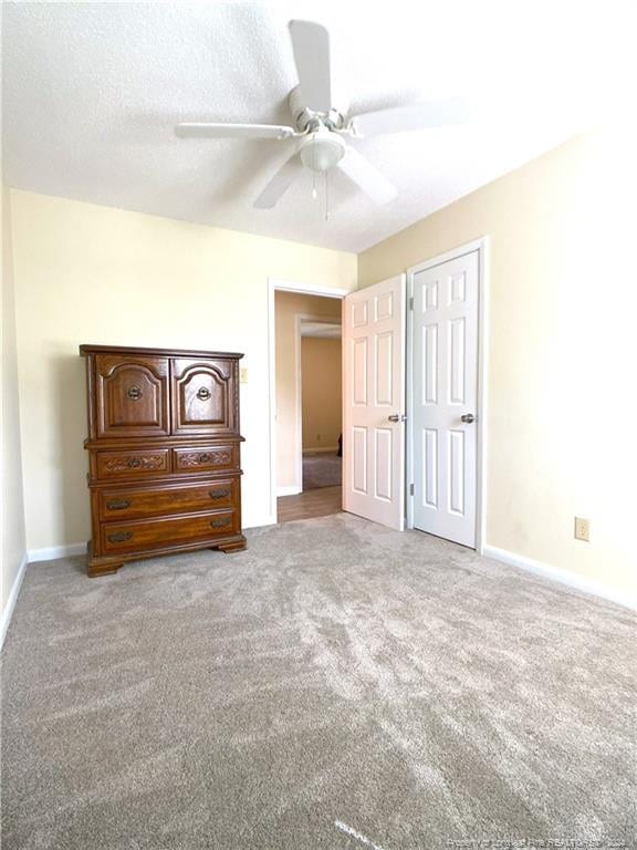 unfurnished bedroom with ceiling fan, a textured ceiling, and light carpet