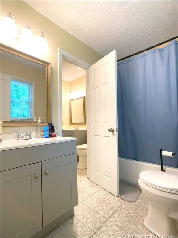 full bathroom featuring vanity, toilet, a textured ceiling, tile patterned flooring, and shower / tub combo with curtain