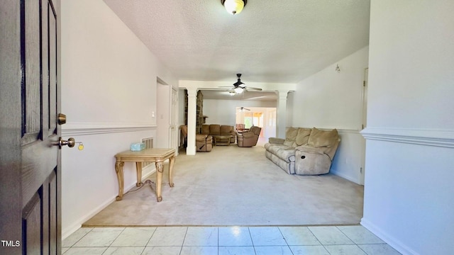 sitting room with a textured ceiling, decorative columns, light carpet, and ceiling fan