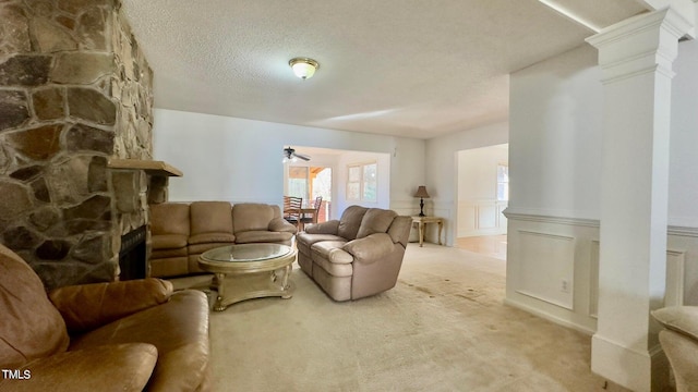 living room featuring a textured ceiling, ceiling fan, light colored carpet, and a stone fireplace