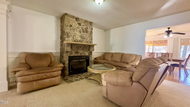 living room featuring a textured ceiling, carpet, a fireplace, and ceiling fan