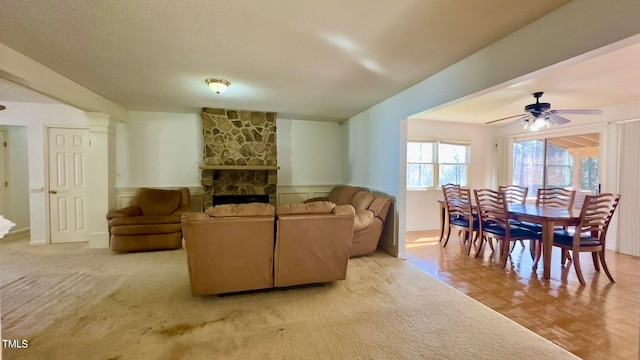 living room featuring a textured ceiling, a fireplace, light parquet flooring, and ceiling fan