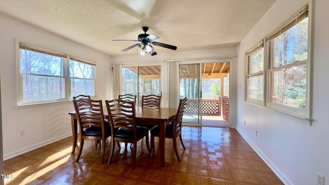 dining space with a textured ceiling, dark parquet flooring, ceiling fan, and plenty of natural light