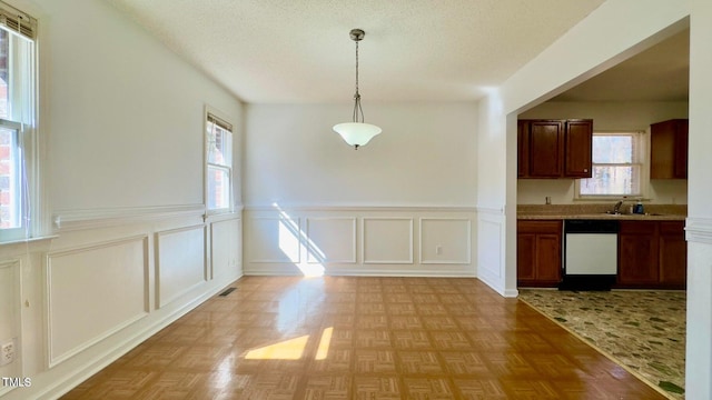 unfurnished dining area with light parquet floors, a healthy amount of sunlight, and sink