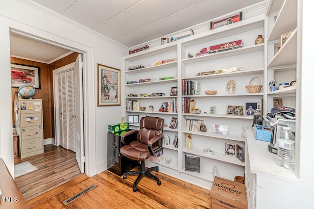 office with wooden walls, crown molding, and light wood-type flooring