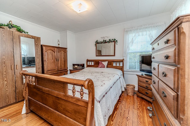 bedroom with crown molding and light wood-type flooring