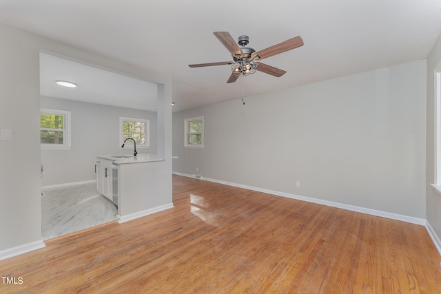 empty room with light wood-type flooring, sink, and ceiling fan