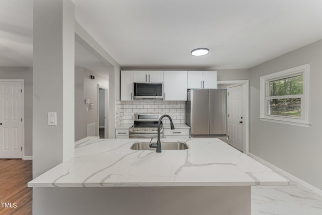 kitchen with wood-type flooring, sink, white cabinetry, appliances with stainless steel finishes, and light stone countertops