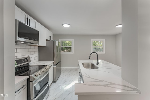 kitchen with light stone counters, sink, tasteful backsplash, white cabinetry, and stainless steel appliances