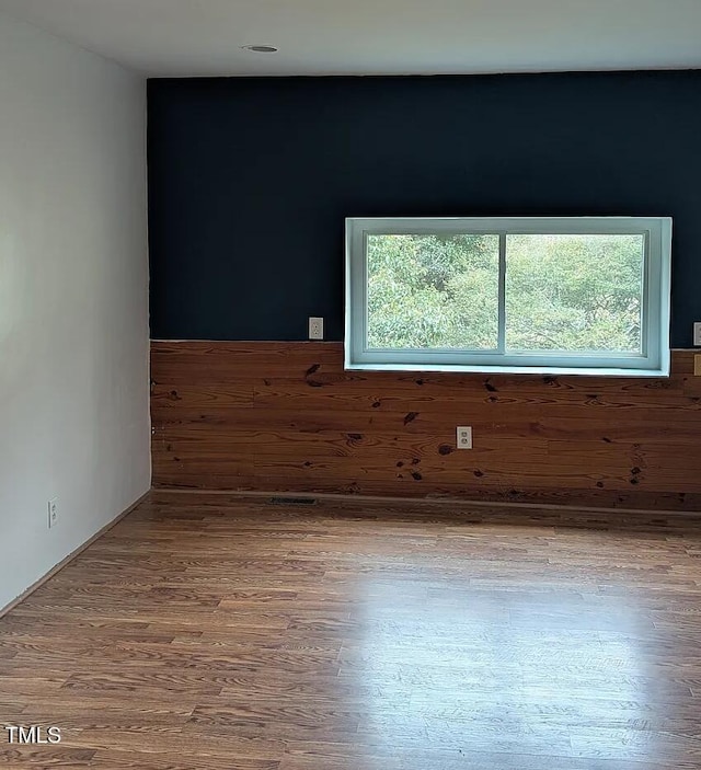 unfurnished room featuring wooden walls and wood finished floors