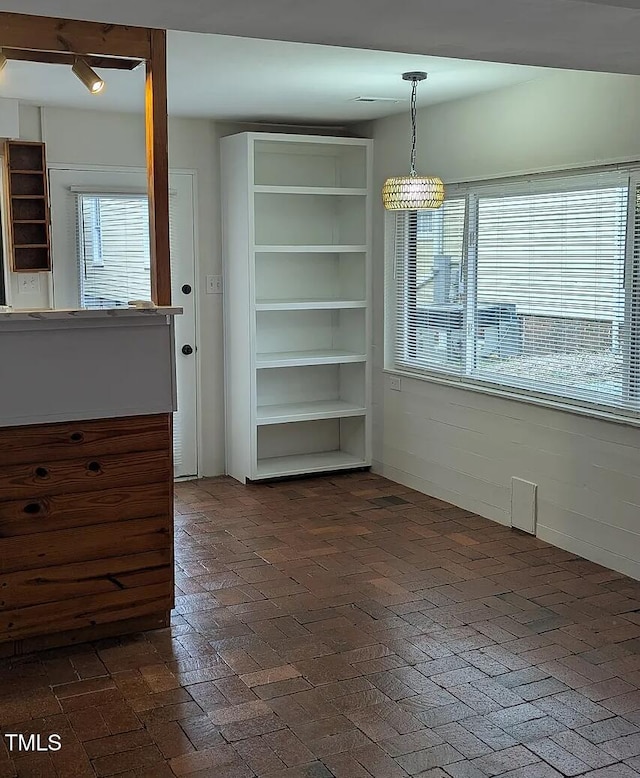 unfurnished dining area featuring brick floor