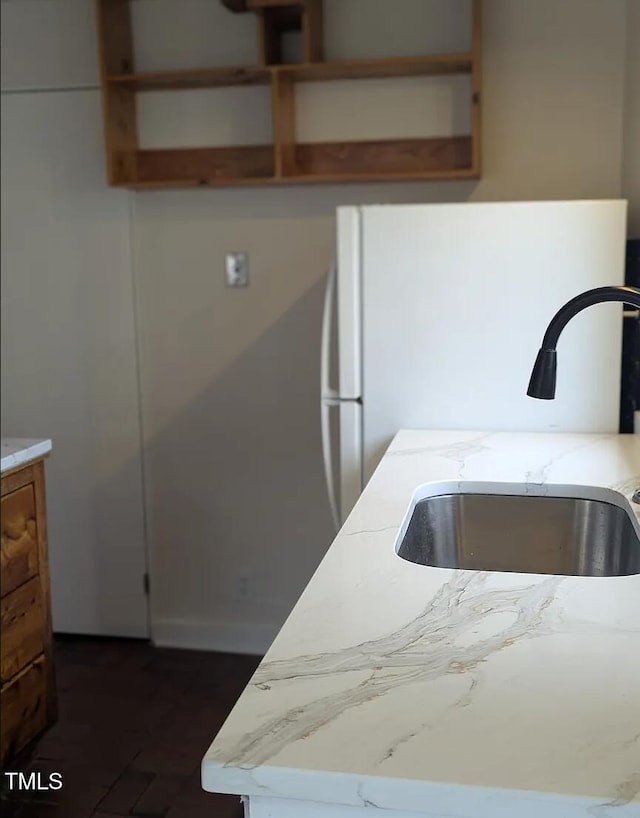 kitchen featuring light stone countertops, open shelves, and a sink