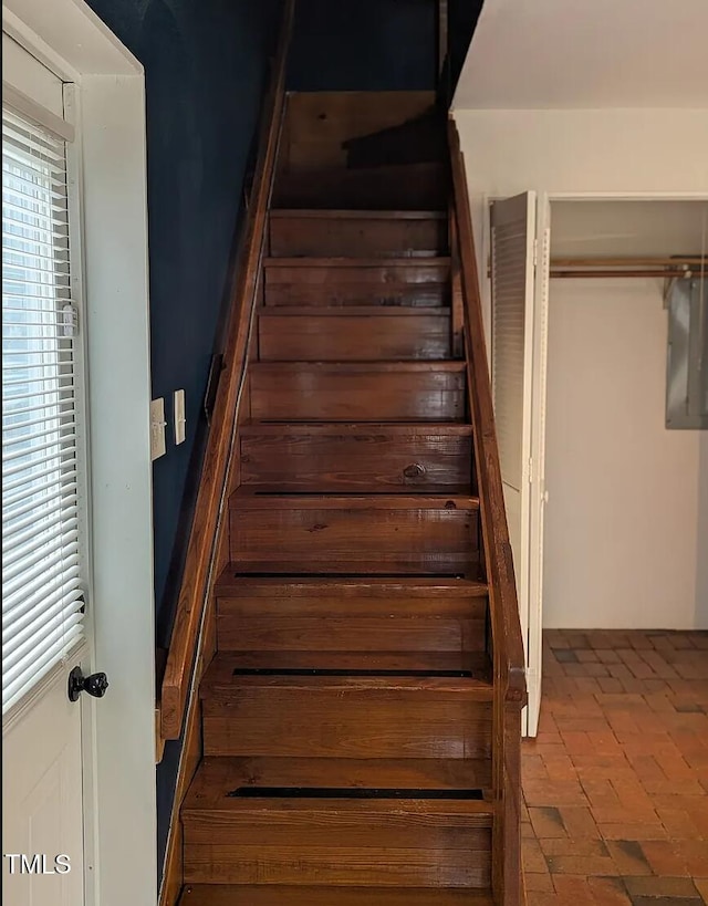 stairway featuring plenty of natural light and brick floor