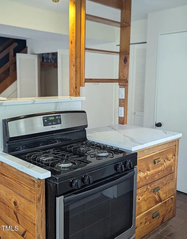 kitchen with light stone countertops, brick floor, brown cabinets, and gas stove