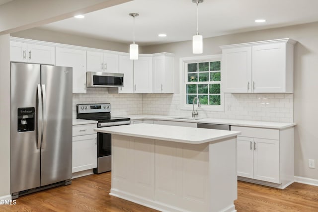 kitchen featuring sink, appliances with stainless steel finishes, pendant lighting, white cabinets, and light wood-type flooring