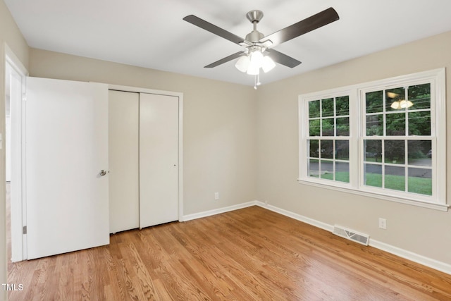 unfurnished bedroom with ceiling fan, a closet, and light wood-type flooring